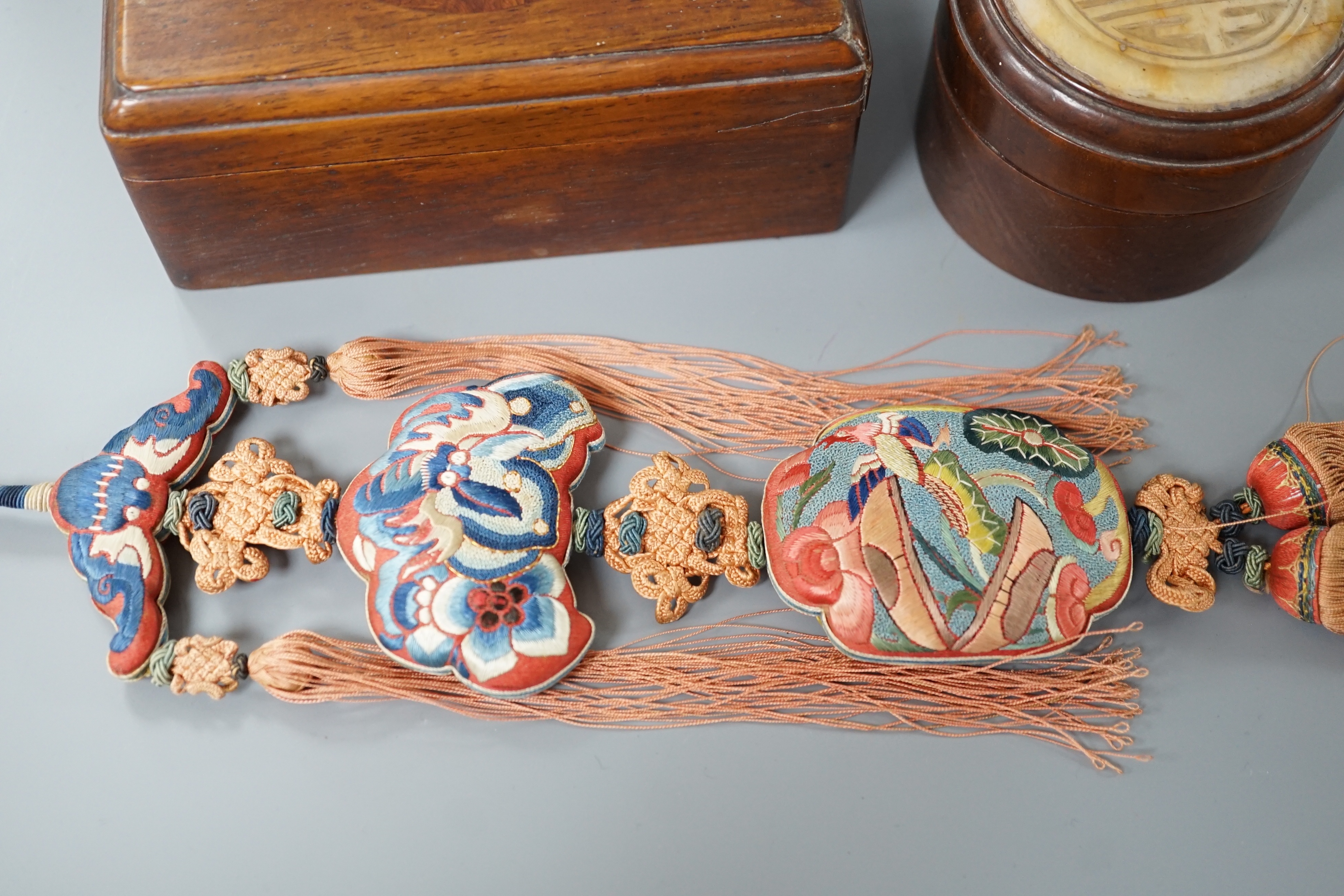 Two 19th century Chinese hardstone inset hardwood boxes and an embroidered amulet charm, largest box 12.5cm